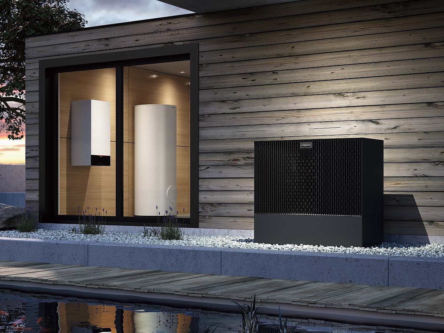 Moderne Wärmepumpe vor einem stilvollen Holzhaus Die Außenansicht eines Hauses mit einer eleganten Wärmepumpe und zwei weißen Heizgeräten hinter einer großen Glasfront.