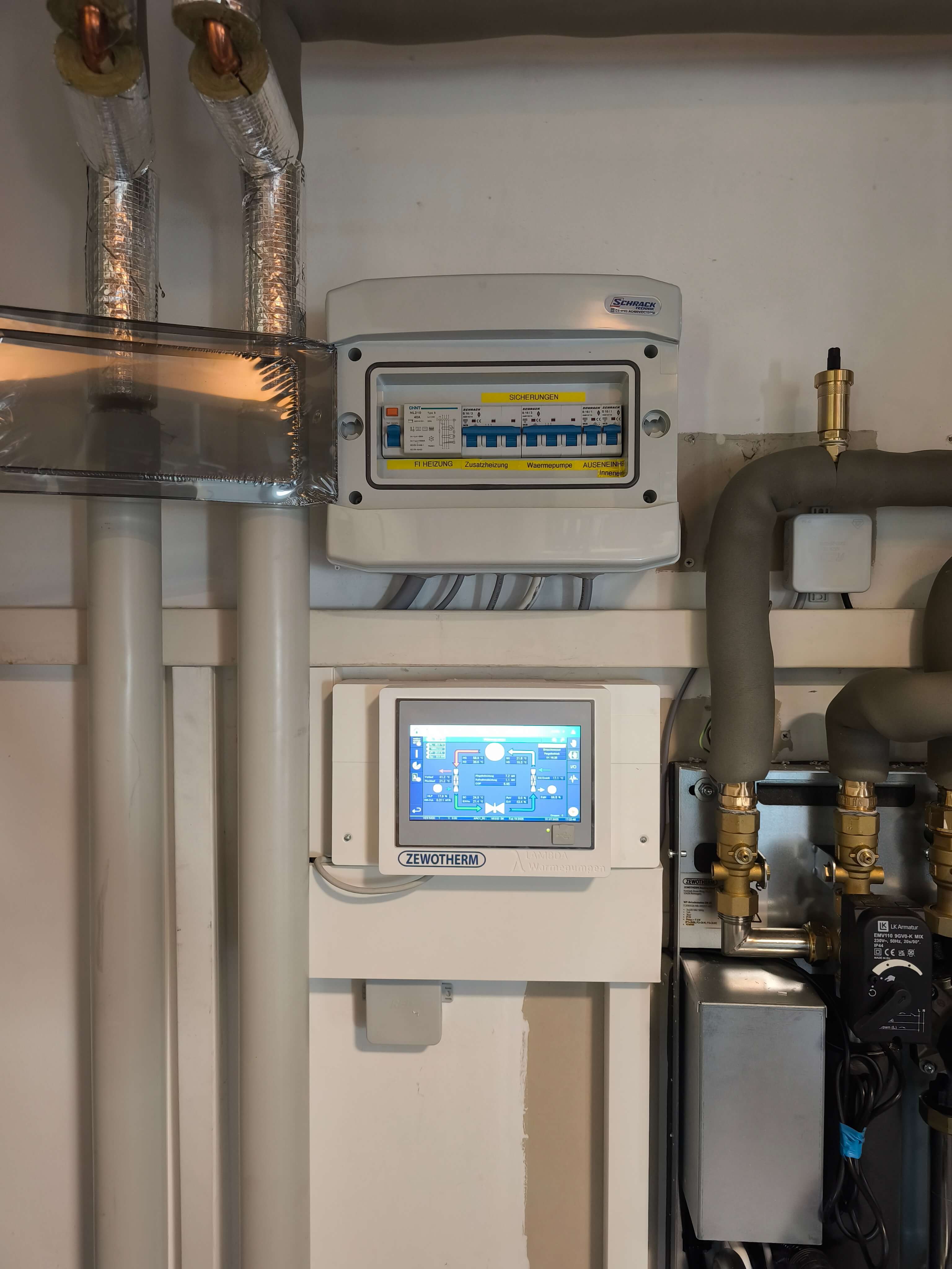 Moderne Heizungssteuerung mit digitalem Display für Wärmepumpen In einem Technikraum sind Heizungsrohre und ein Steuergerät für die Wärmepumpe montiert, das die Temperaturregelung anzeigt.